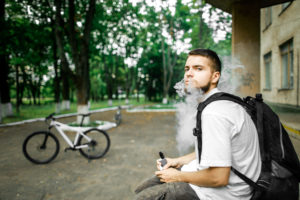 Man with beard and smoke. Thick steam. Bicycle. Vape.